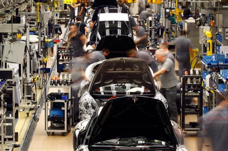 Workers assemble cars at a factory