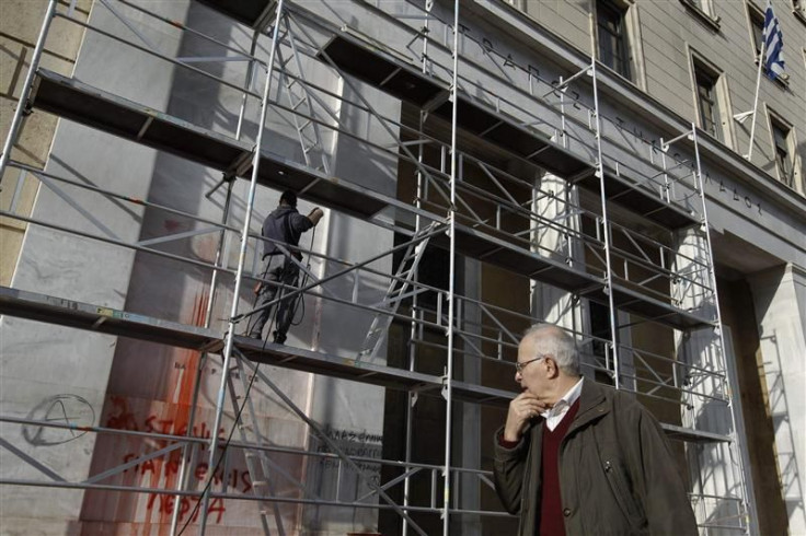 Man walks past Bank of Greece as cleaning works are in progress after Sunday&#039;s violent protests in Athens