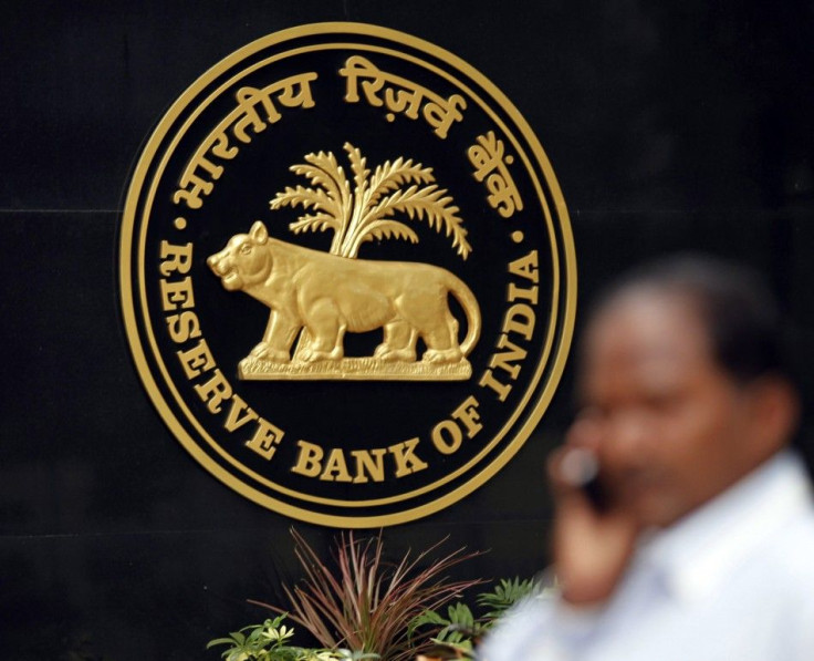 A man talks on his mobile phone as he walks past the logo of the Reserve Bank of India (RBI) inside its head office in Mumbai