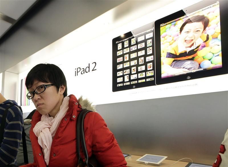 A customer pauses while testing out an Apple iPad 2 in the companys flagship store in Beijings Sanlitun Area