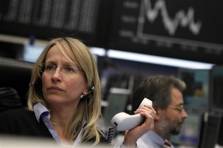 Traders work at their desks in front of the DAX board at the Frankfurt stock exchange