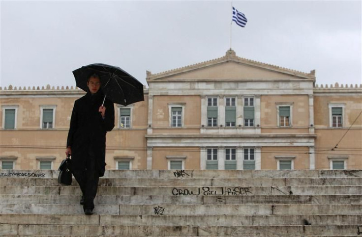 A man makes his way during a rainy day in front of the parliament in Athens