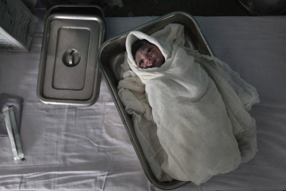 An underweight newborn lies in a tray inside a hospital delivery room in northwestern India