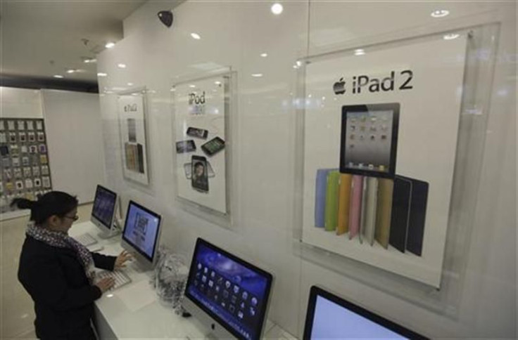 Apple iPad posters are seen at a dealership as a customer tries out an Apple Mac in Wuhan