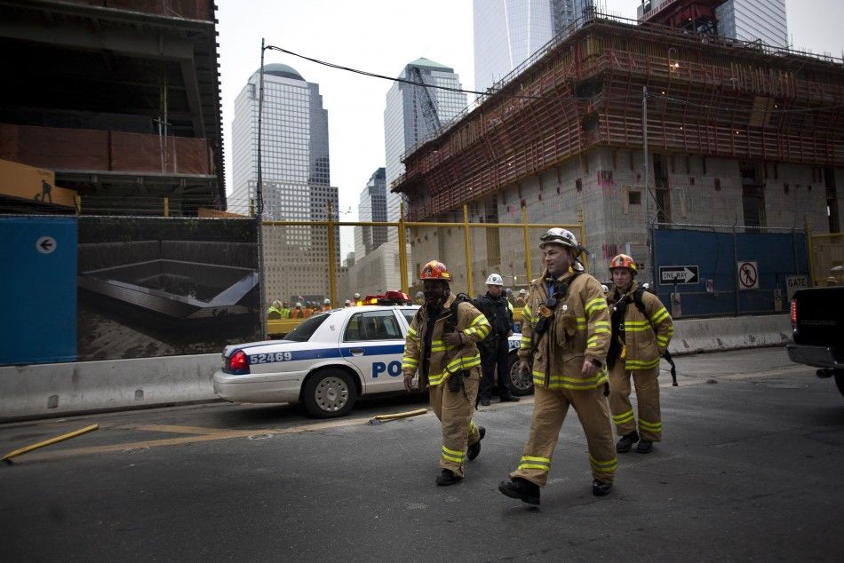 Firefighters walk near the World Trade Center construction site after a large column fell 40 stories in New York