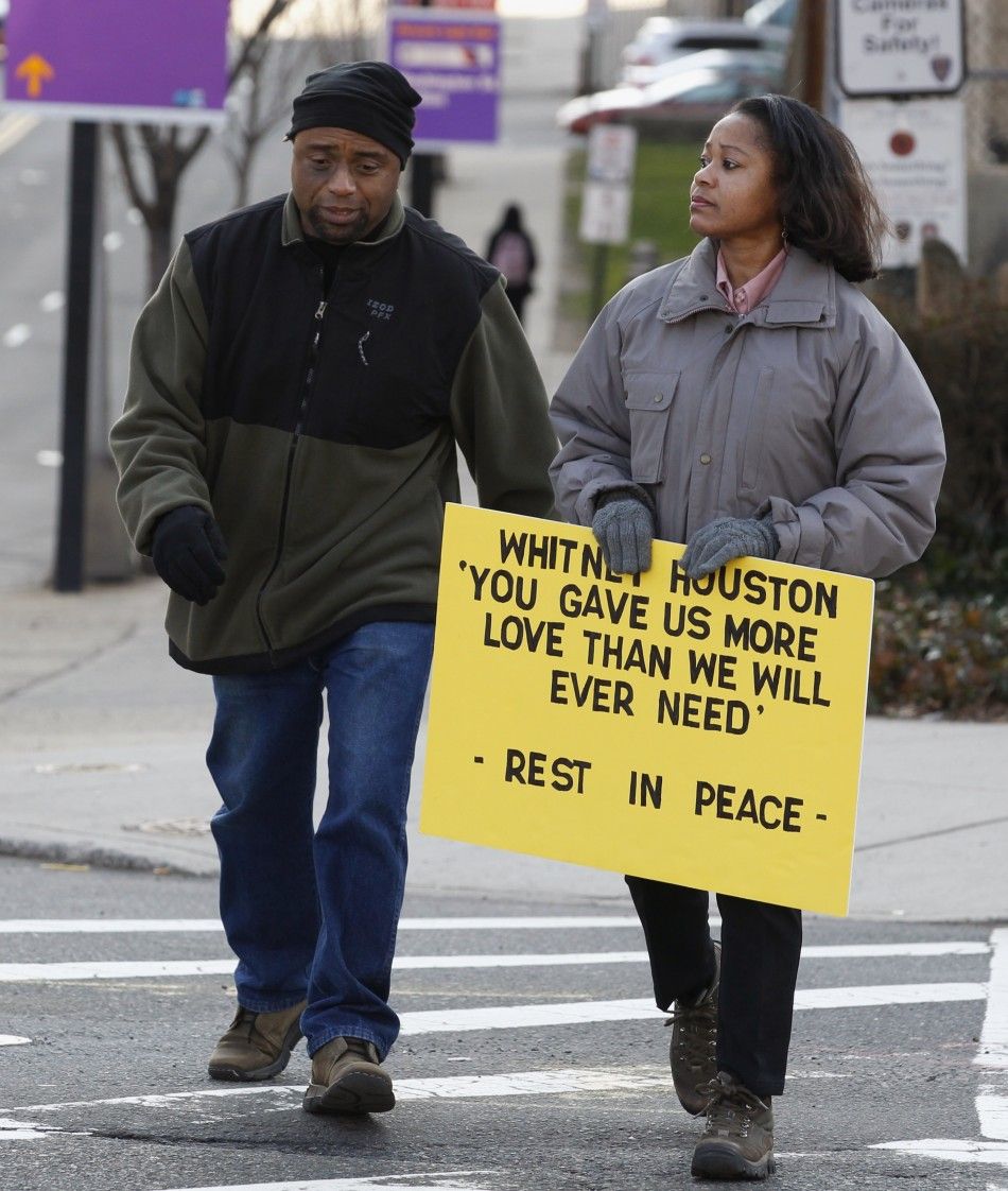 Woman carries a sign in tribute to the late singer Houston near New Hope Baptist Church before her funeral service in Newark