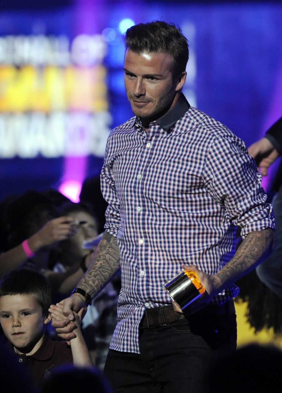 David Beckham holds his son Cruzs hand as he accepts the Thats How I Roll award