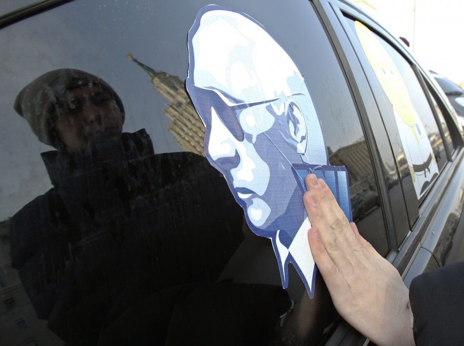 A man sticks a portrait of Russias Prime Minister Vladimir Putin on a car before a car rally to show support for Putins presidential candidacy in Moscow Feb. 18, 2012. Russia will go to the polls for a presidential election on March 4.