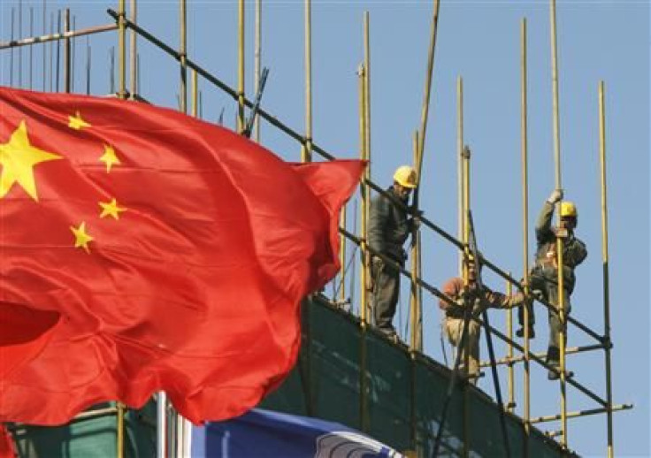 Workers install scaffolding at a construction site as a Chinese national flag flies near by in central Beijing