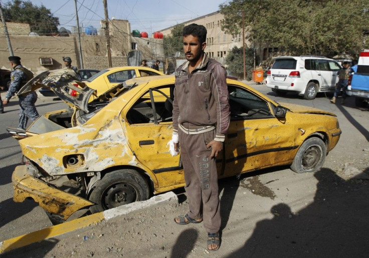 A man stands near his damaged vehicle after a bomb attack in Baghdad&#039;s Karrada district
