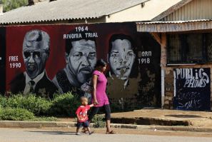 A women and her child walk past portraits of former South African President Nelson Mandela, painted by O.J. Zwane, in Soweto February 26, 2012.