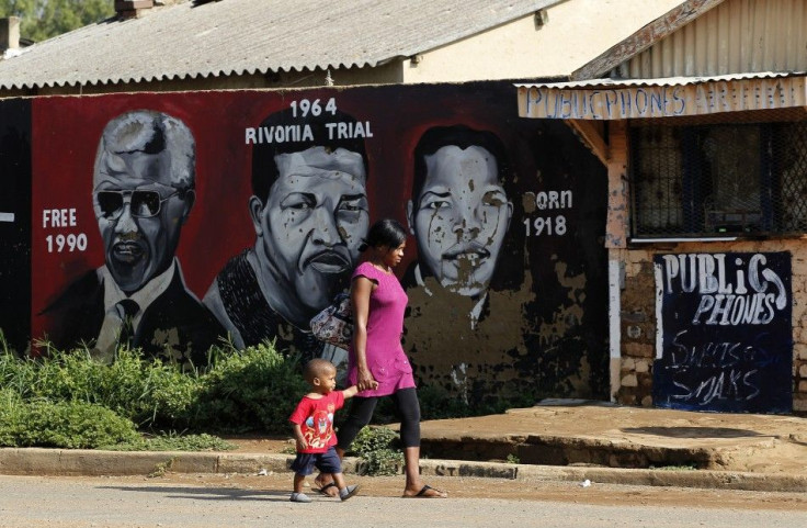 A women and her child walk past portraits of former South African President Nelson Mandela, painted by O.J. Zwane, in Soweto February 26, 2012.