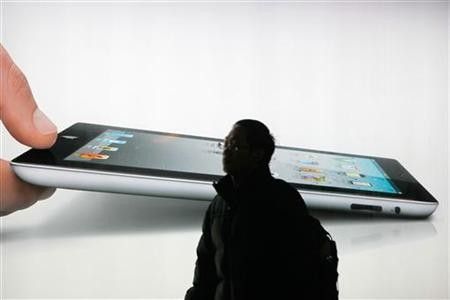 A man walks past an iPad 2 advertisement in Shanghai February 21, 2012.