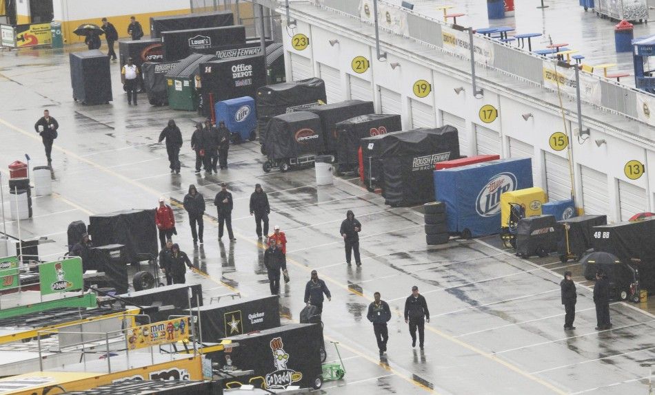 Pit crew members walk in the garage area as rain delayed the start of the NASCAR Sprint Cup Series 54th Daytona 500 race at the in Daytona Beach