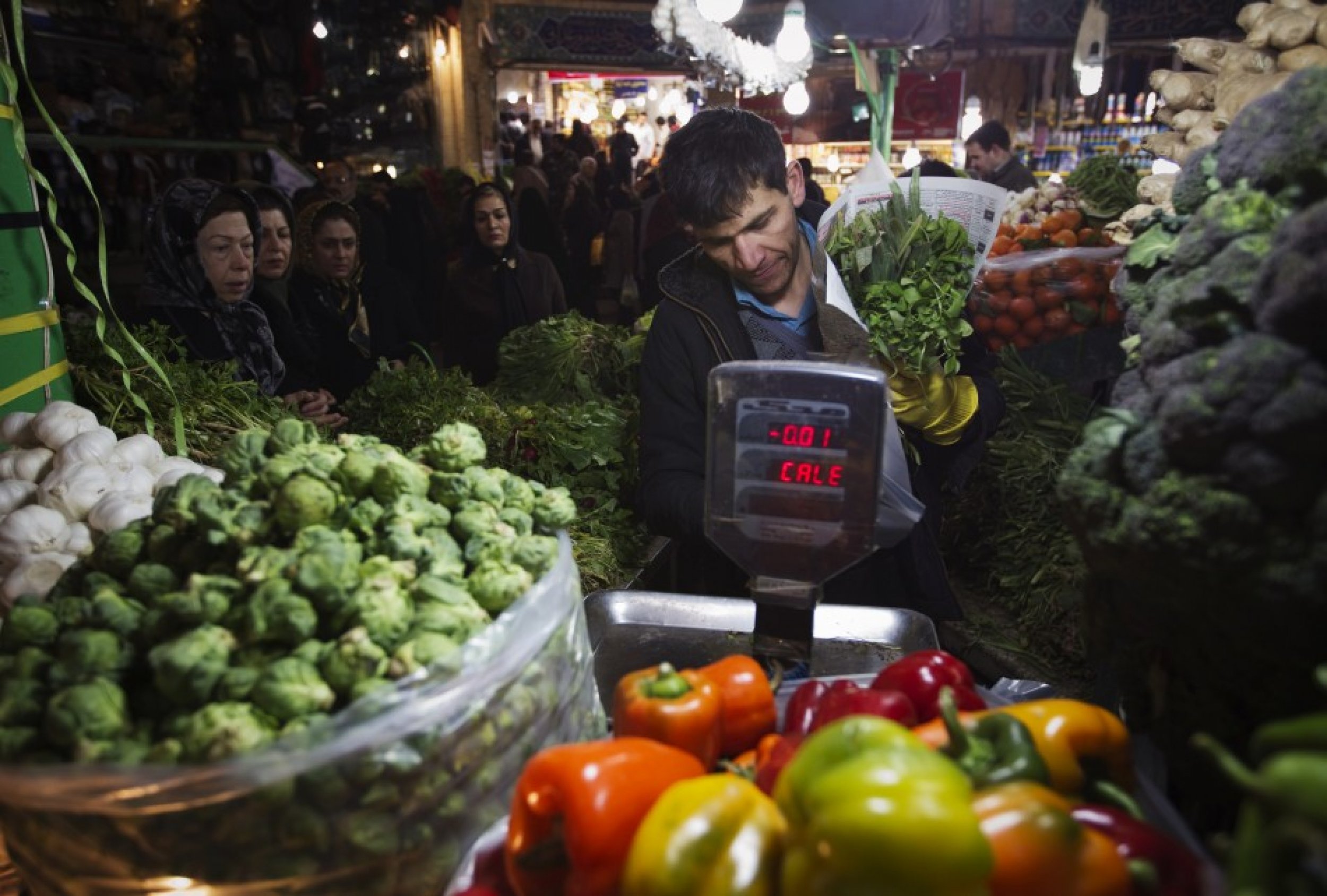 A shopkeeper checks the prices of vegetables for a customer at a bazaar in northern Tehran