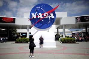 Tourists take pictures of a NASA sign at the Kennedy Space Center visitors' complex in Cape Canaveral, Fla.