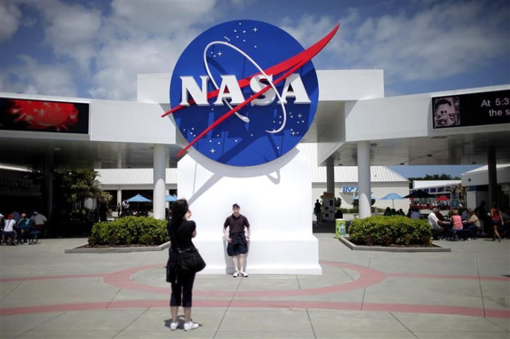 Tourists take pictures of a NASA sign at the Kennedy Space Center visitors' complex in Cape Canaveral, Fla.