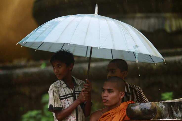 A Bangladeshi Buddhist monk collects alms with children as it rains in Cox's Bazar October 3, 2012, after Muslims attacked and set fire to a temple. 