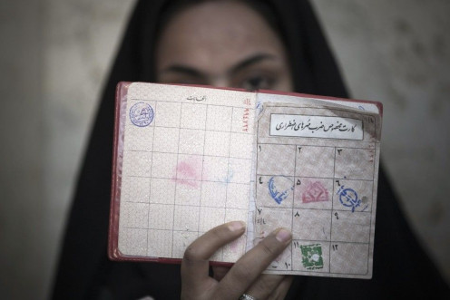 A woman holds her identification in front of her face as she rests after voting at a polling station during Iran&#039;s parliamentary election in southern Tehran March 2, 2012.