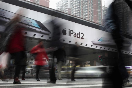 People walk past an Apple billboard advertising the iPad 2 in downtown Shanghai.