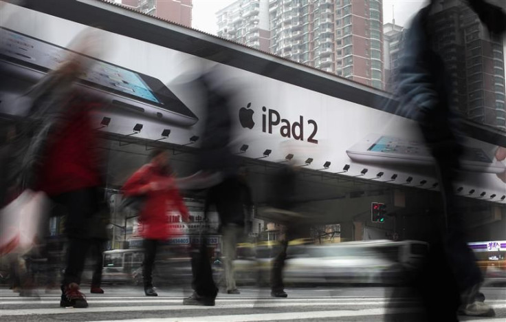 People walk past an Apple billboard advertising the iPad 2 in downtown Shanghai.