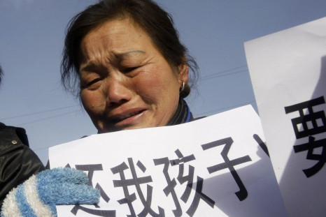 A woman, whose child died from drinking tainted milk, holds a sign outside Shijiazhuang Intermediate People's Court