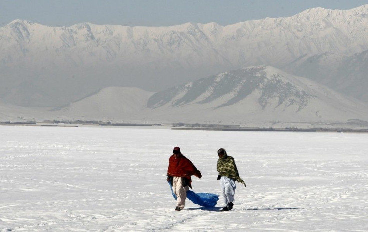 Afghan residents walk on a snow covered field near Bagram highway in Afghanistan