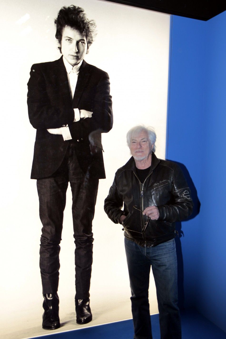French singer Hugues Aufray poses in front of a photograph of Dylan at the museum of the Cite de la Musique in Paris