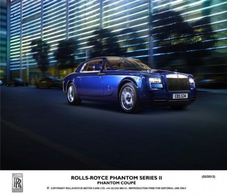 A Rolls-Royce Phantom Series II drives with its headlights on at night.
