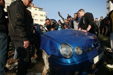 Hamas policemen inspect the remains of a vehicle after it exploded in Gaza City