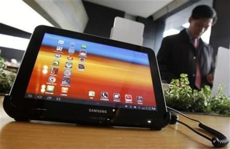 A visitor looks around behind Samsung Electronics' Galaxy Tab 10.1 tablet displayed for customers at a registration desk at South Korean mobile carrier KT's headquarters in Seoul December 9, 2011.