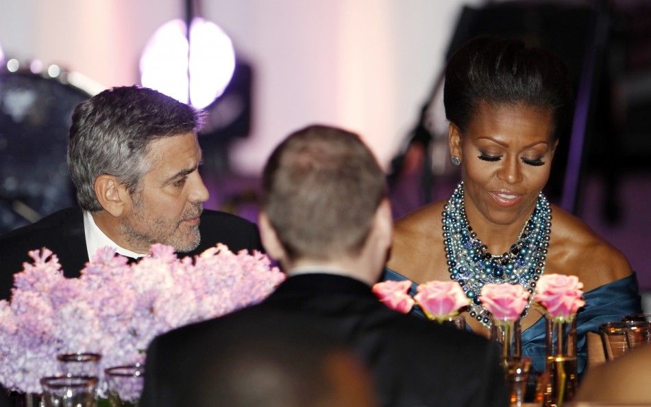 Actor George Clooney sits beside first lady Michelle Obama during the State Dinner for British Prime Minister David Cameron at the White House in Washington March 14, 2012.