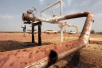 Oil spills onto the ground from an oil well head strafed by shrapnel from a bomb dropped by fighter jets at the El Nar oil field in South Sudan's Unity State
