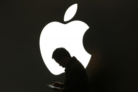 A man looks at his Apple iPad in front an Apple logo outside an Apple store in downtown Shanghai
