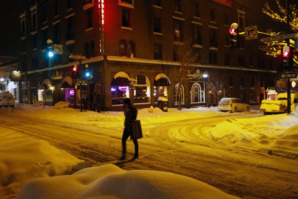 A pedestrian crosses an intersection where several inches of snow have covered the ground in Flagstaff, Arizona, March 18, 2012. The late winter storm kept temperatures well below normal in California on Sunday and generated heavy snow fall in several sta