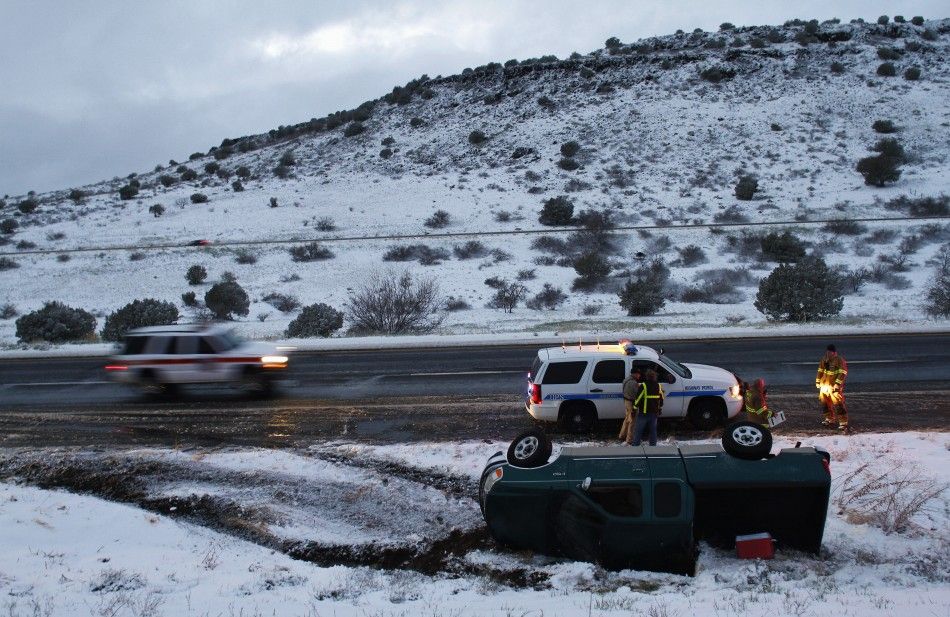 Firefighters and police officers stand near a pick-up truck that rolled on its side after the driver lost control along Interstate-17 in Yavapai County, Arizona, March 18, 2012. The late winter storm kept temperatures well below normal in California on Su