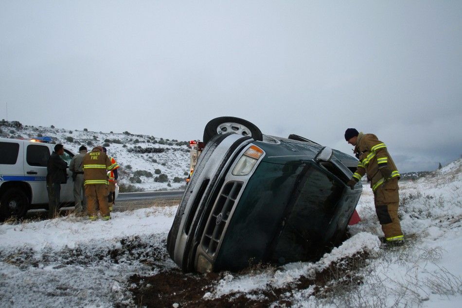 A firefighter looks into the passenger side of a pick-up truck that rolled on its side after the driver lost control along Interstate-17 in Yavapai County, Arizona March 18, 2012. The late winter storm kept temperatures well below normal in California on 