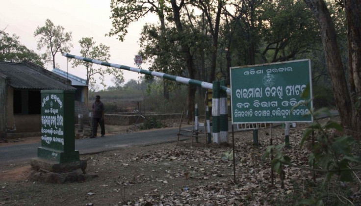 A man walks under a barricade pole installed to check passing vehicles by Indian forest officials at the remote district of Kandhamal