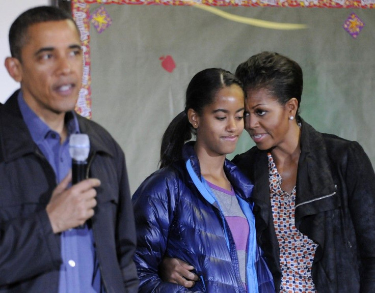 Michelle Obama stands with her daughter Malia as Obama delivers remarks during a day of service to honor Martin Luther King, Jr, at a school in Washington