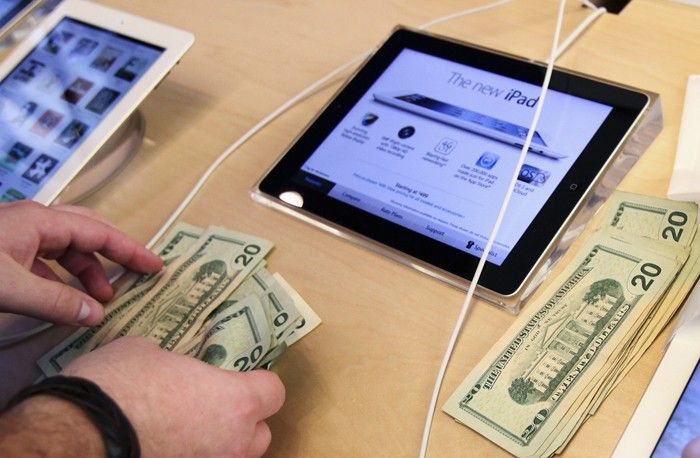 An Apple employee counts money as a customer purchases Apples new iPad at the 5th Avenue Apple Store in New York
