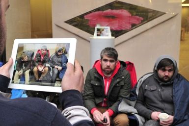 A man uses his iPad to photograph customers who have slept outside a store for 48 hours waiting to purchase new Apple iPad tablet computers in central London