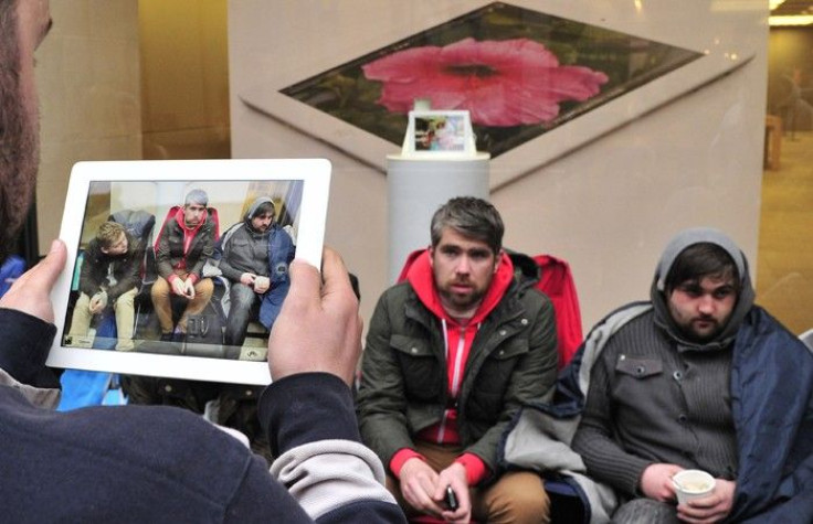 A man uses his iPad to photograph customers who have slept outside a store for 48 hours waiting to purchase new Apple iPad tablet computers in central London
