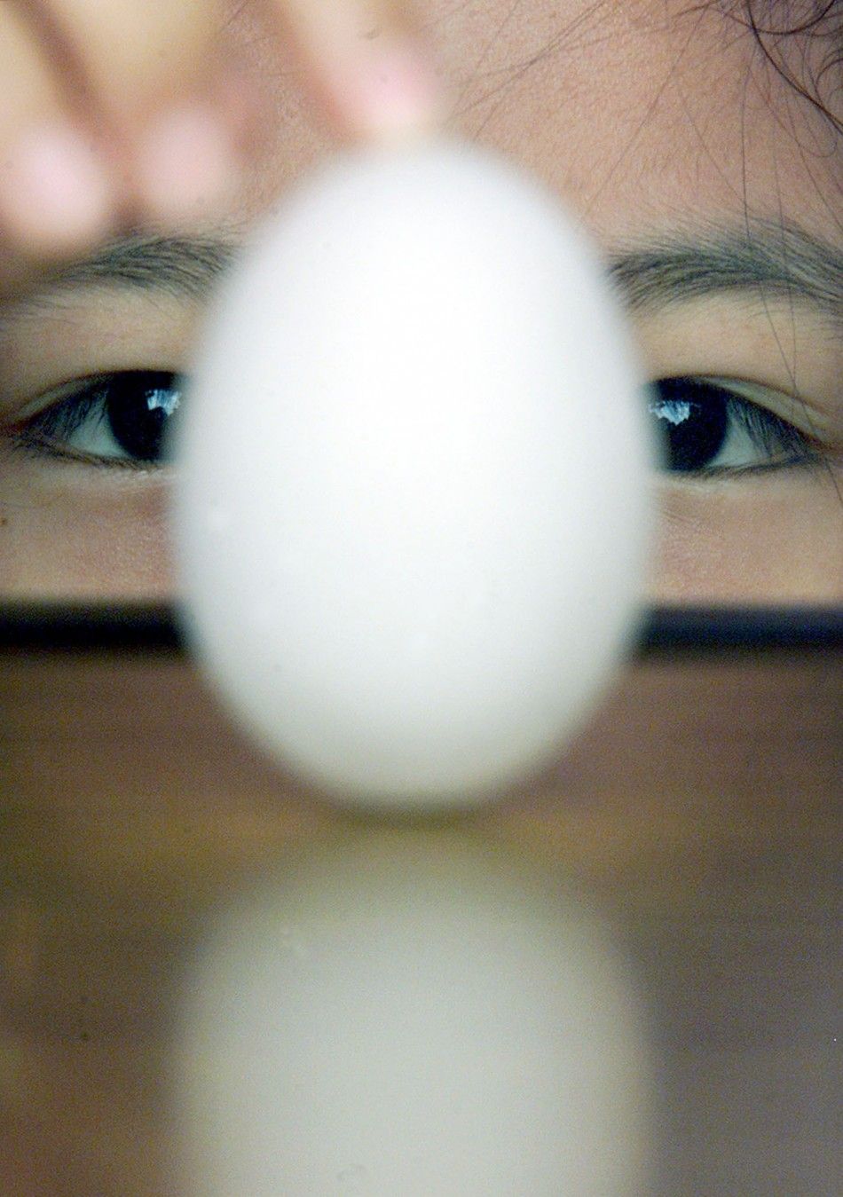 A Taiwanese girl balances an egg on its end at a playground in Taipei June 25, 2001. 