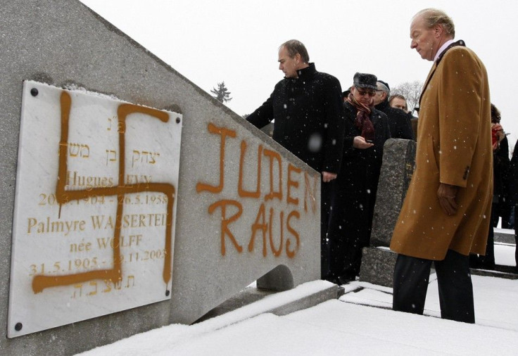 France&#039;s Interior Minister Hortefeux walks next to a tombstone desecrated by vandals with Nazi swastikas and the Slogan &quot;Jews out&quot;, in the Jewish Cemetery of Cronenbourg