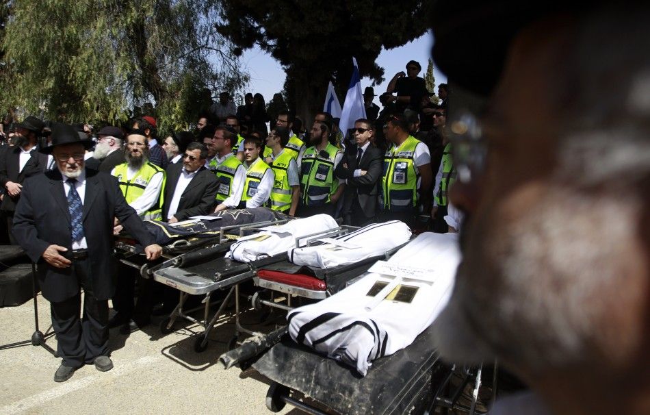 People stand around the bodies of victims of Mondays shooting in Toulouse, during their joint funeral service in Jerusalem