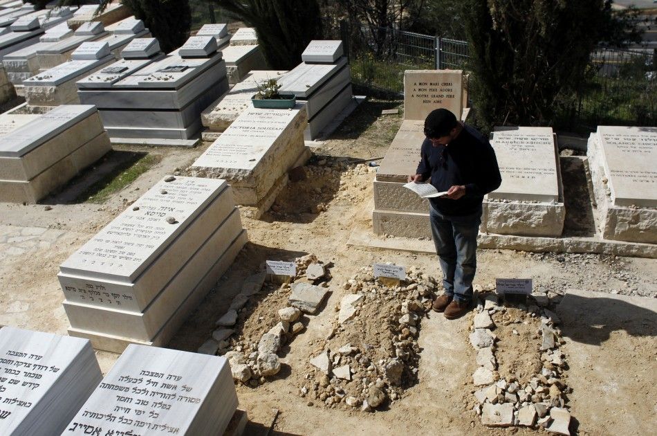 A mourner stands over the fresh graves of victims of Mondays shooting in Toulouse, after their joint funeral in Jerusalem
