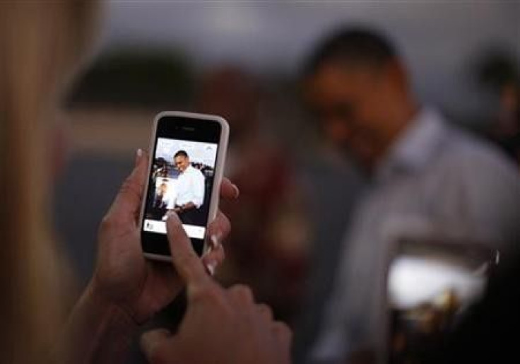A woman takes a picture of U.S. President Barack Obama with her iPhone upon his arrival at Hickam Air Base near Honolulu, Hawaii, December 23, 2011.