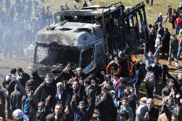 Kurdish demonstrators flash victory signs in front of a burnt-out vehicle in Diyarbakir, southeastern Turkey