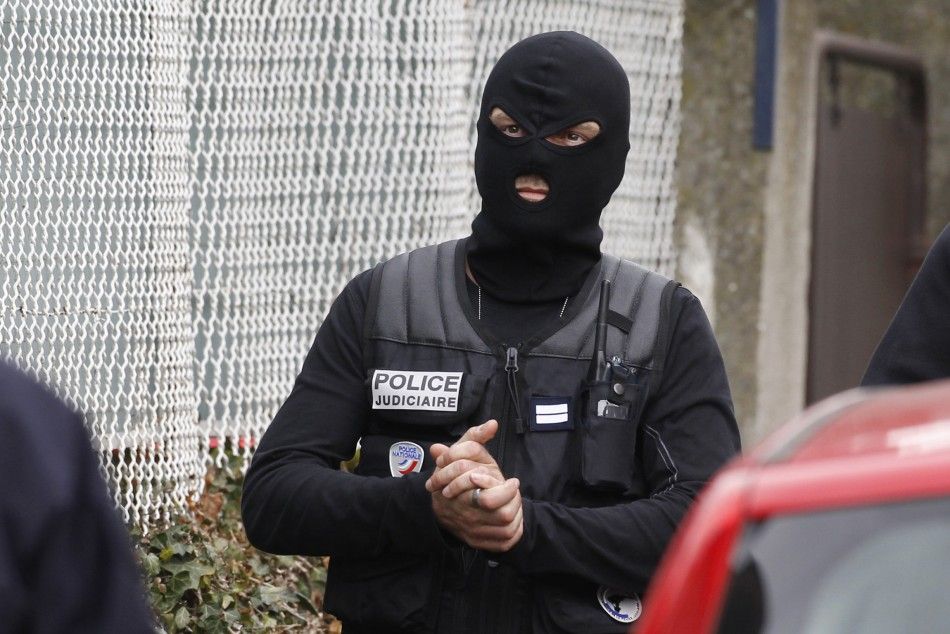 A masked French special unit policeman arrives during a raid on a house to arrest suspects in the killings of three children and a rabbi on Monday at a Jewish school, in Toulouse