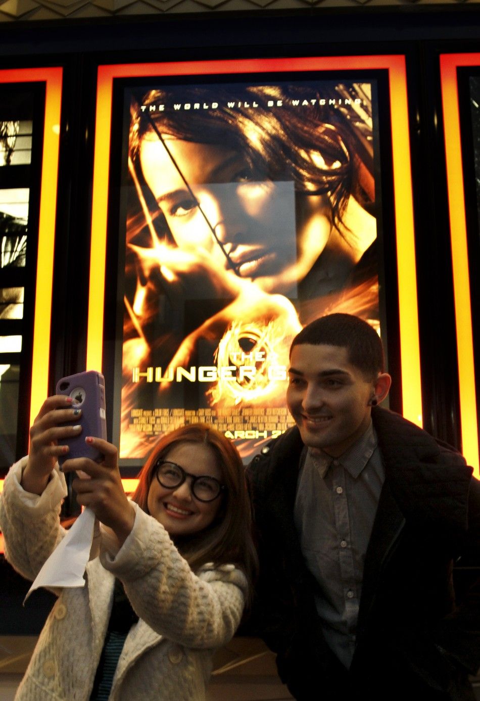 Elizabeth Arellano and Sal Arellano pose for a photo in front of a movie poster of quotThe Hunger Gamesquot at Regal Cinemas in Los Angeles, California March 22, 2012.